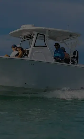 White Tidewater center console boat with black T-top and dual outboard engines cruising on water